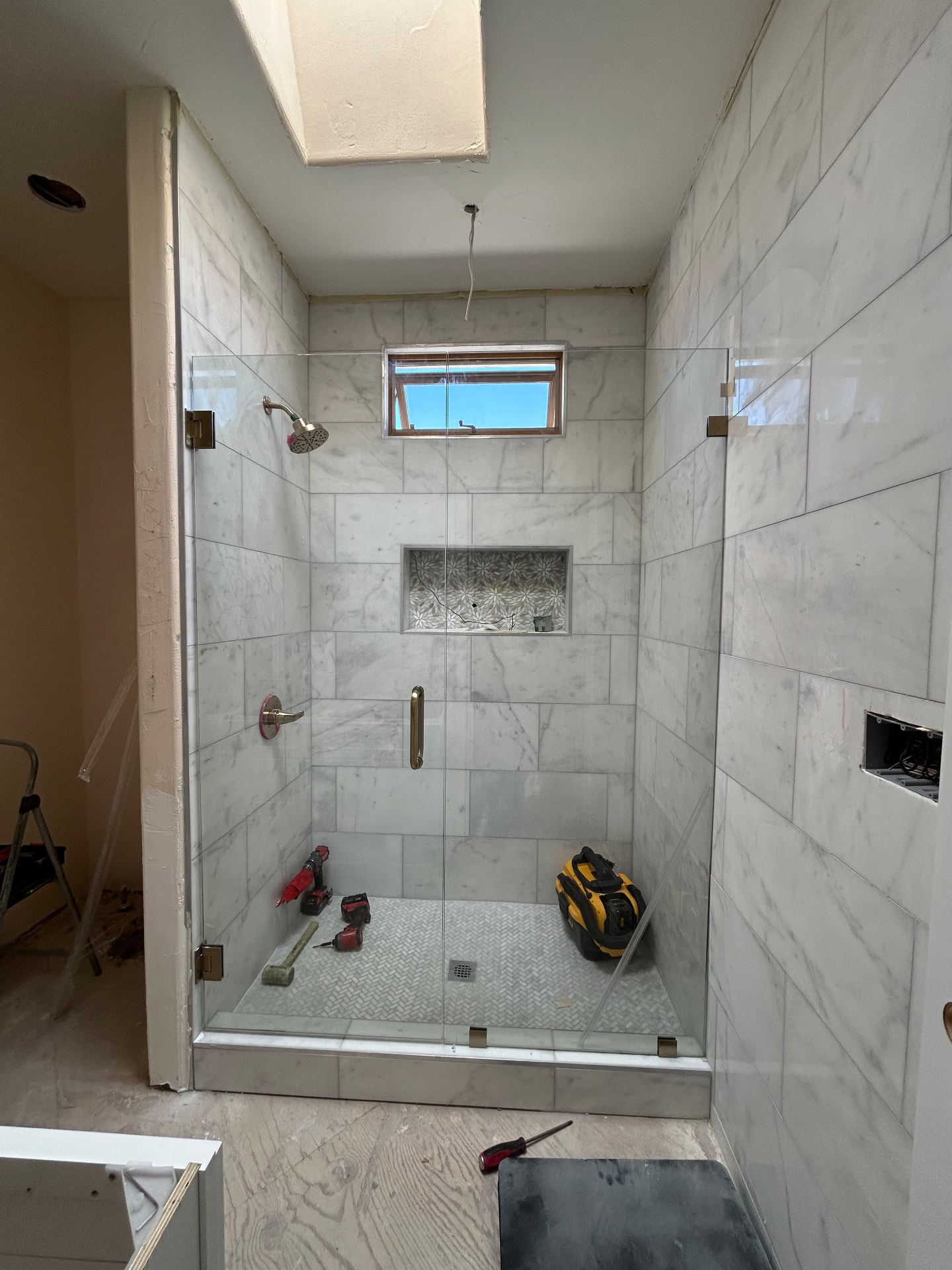 Frameless glass shower enclosure with marble tile
