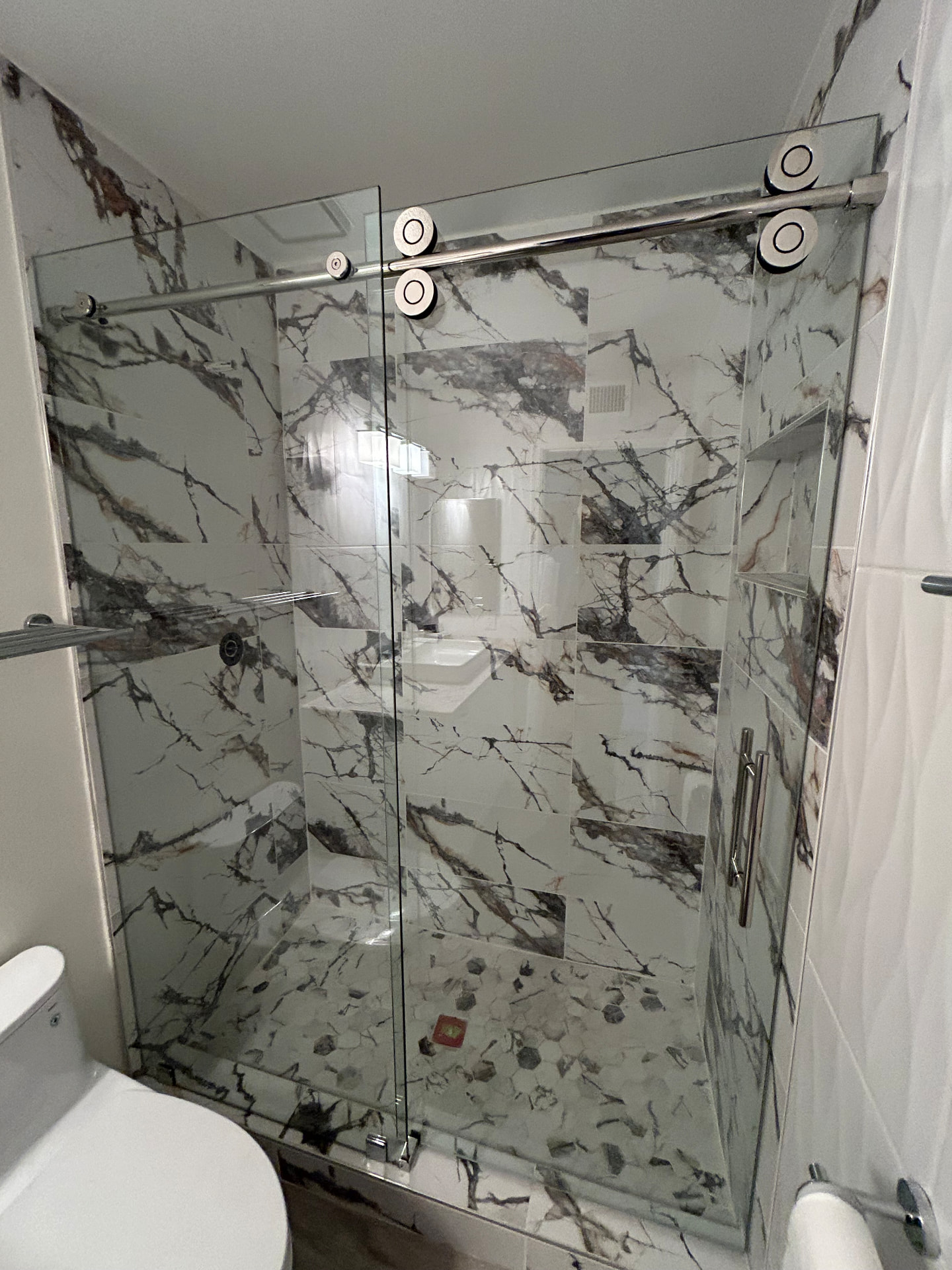 Sliding glass shower door with dramatic marble tile