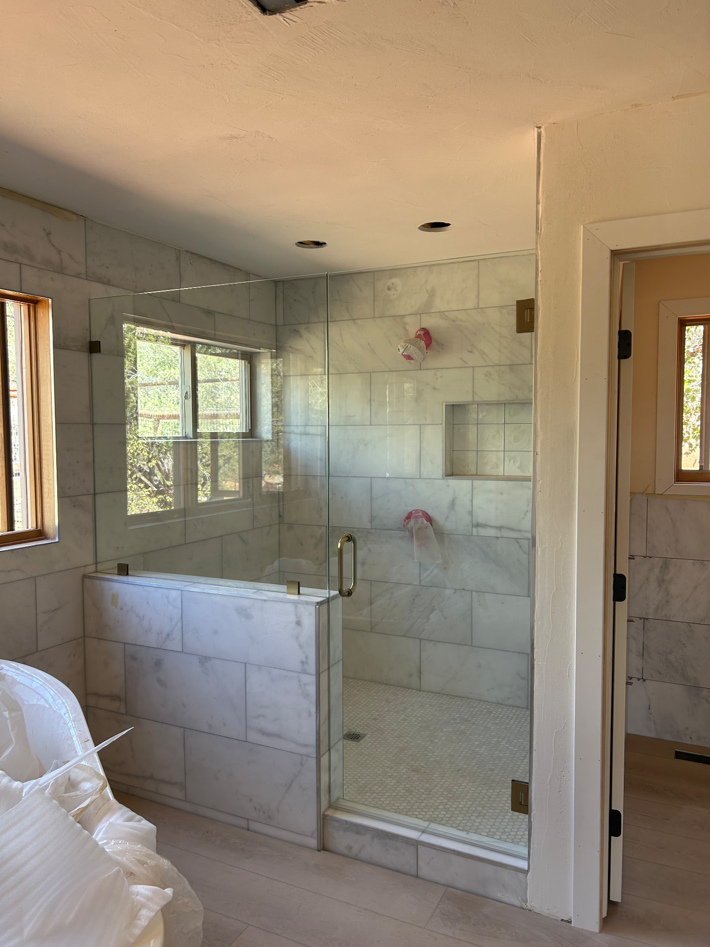 Frameless marble tile shower enclosure with glass door